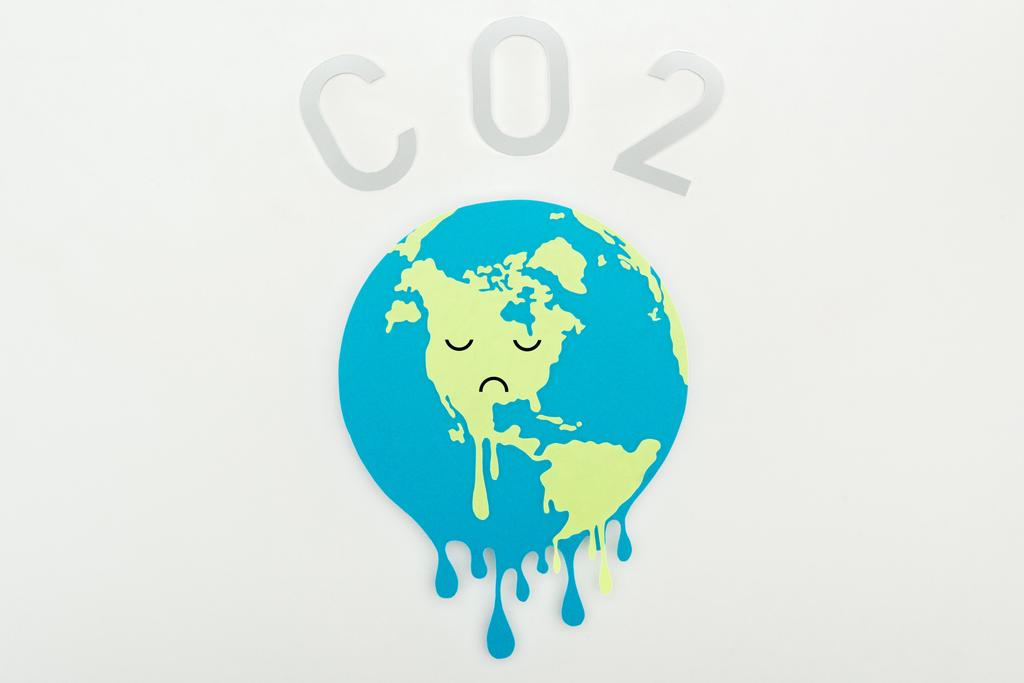 řezání papíru tání země s výrazem smutný obličej a nápis "co2" na šedém pozadí, globální oteplování koncepce - Fotografie, Obrázek