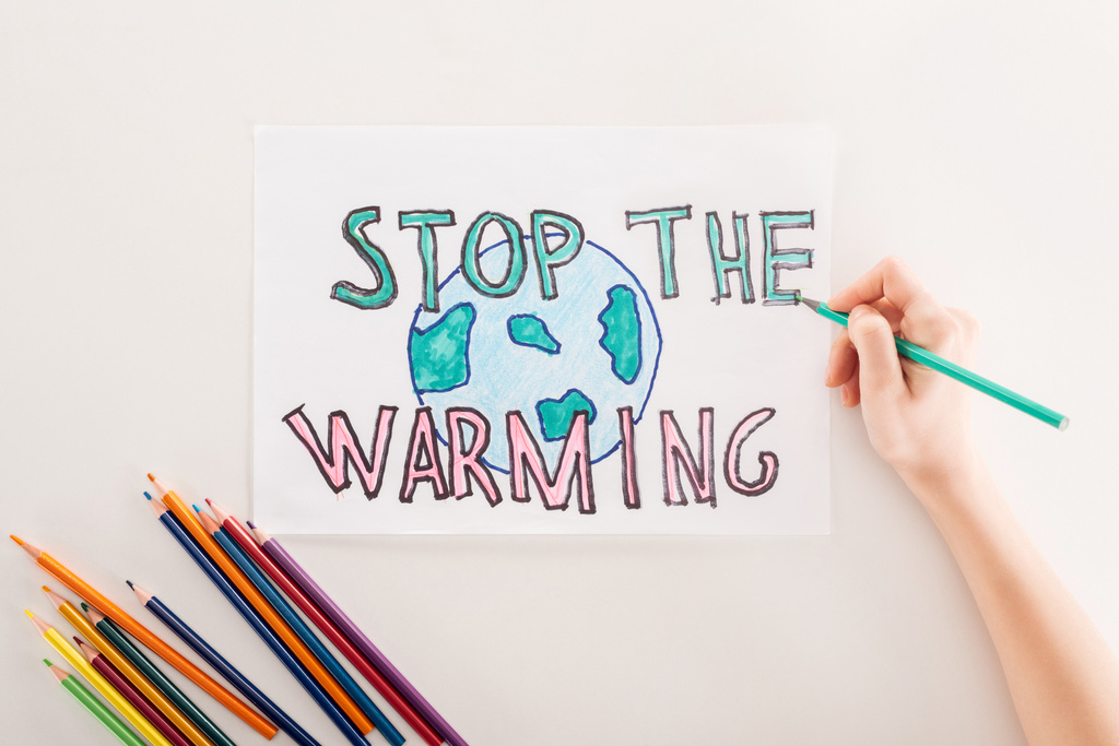 μερική άποψη της γυναίκας που γράφει «να σταματήσει η υπερθέρμανση του πλανήτη» στην κάρτα με το ζώδιο της γης, και πολύχρωμα μολύβια σε άσπρο φόντο - Φωτογραφία, εικόνα