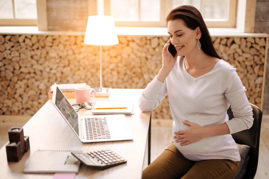 Оптимистичная беременная женщина с помощью телефона
 - Фото, изображение