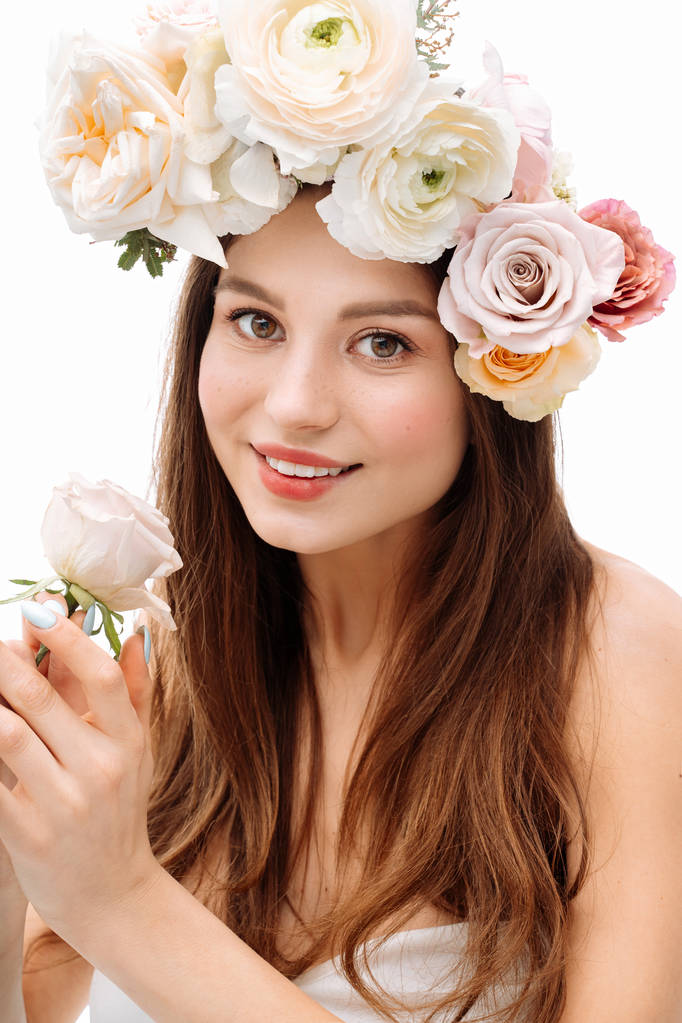 Красива молода дівчина посміхається і позує з квітами на білому тлі в білій сукні. Студійний портрет
. - Фото, зображення