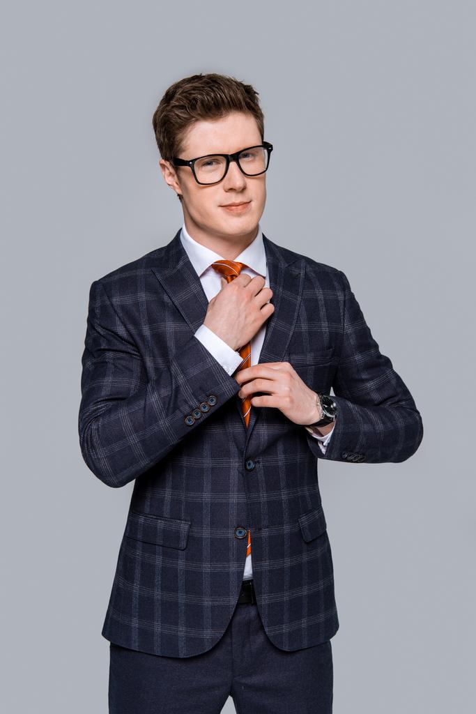 красивий стильний бізнесмен регулює краватку ізольовано на сірому
 - Фото, зображення