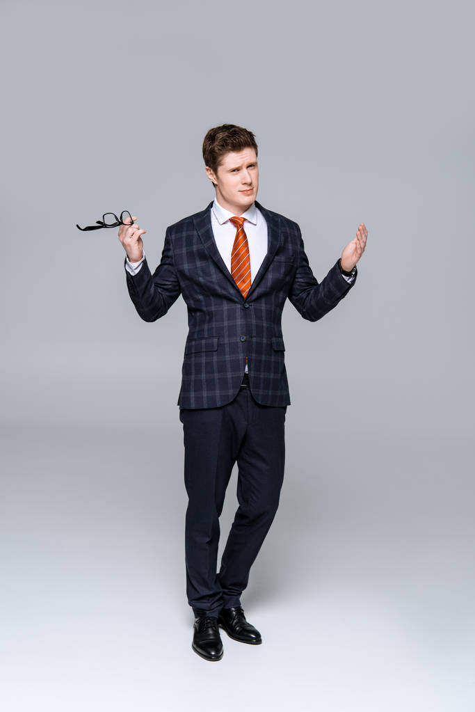 Stilvoller Geschäftsmann im schicken Anzug mit Brille und Schulterzucken - Foto, Bild