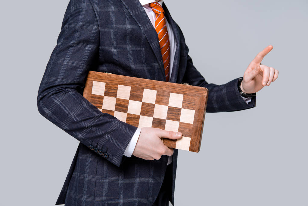 περικοπεί προβολή του επιχειρηματία χειρονομίες και κρατώντας σκακιέρα που απομονώνονται σε γκρι - Φωτογραφία, εικόνα