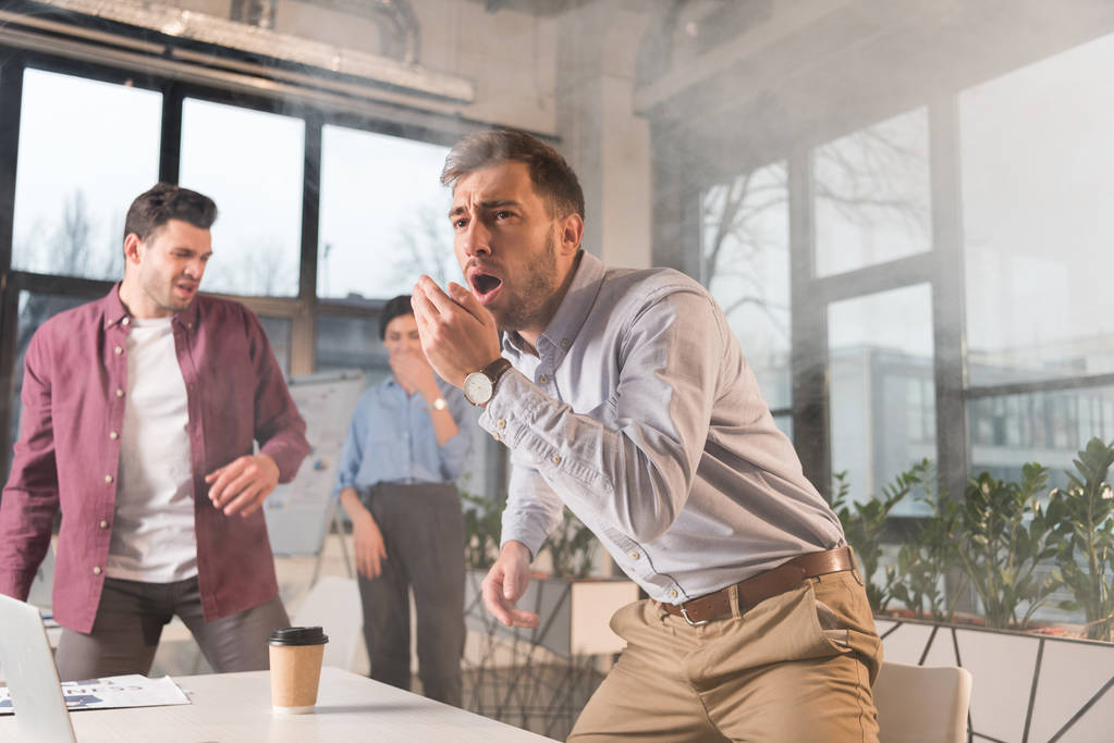 kauhuissaan liikemies seisoo suu auki lähellä kollegoita toimistossa savun
  - Valokuva, kuva