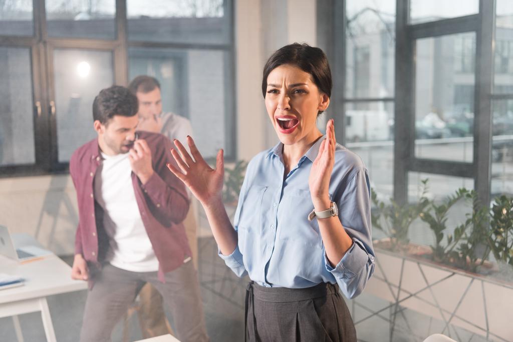 donna d'affari spaventata in piedi urlando vicino ai colleghi in ufficio con il fumo
 - Foto, immagini