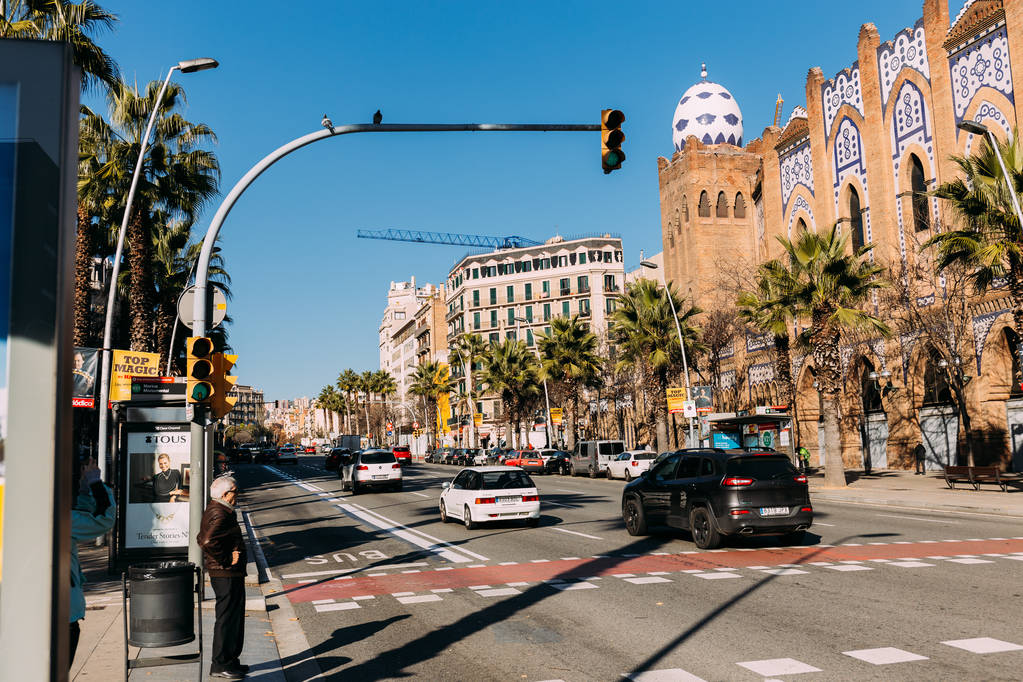 БАРСЕЛОНА, Испания - 28 ДЕКАБРЯ 2018 года: оживленная улица со старым многоцветным зданием и автомобилями, движущимися по широкой дороге
 - Фото, изображение