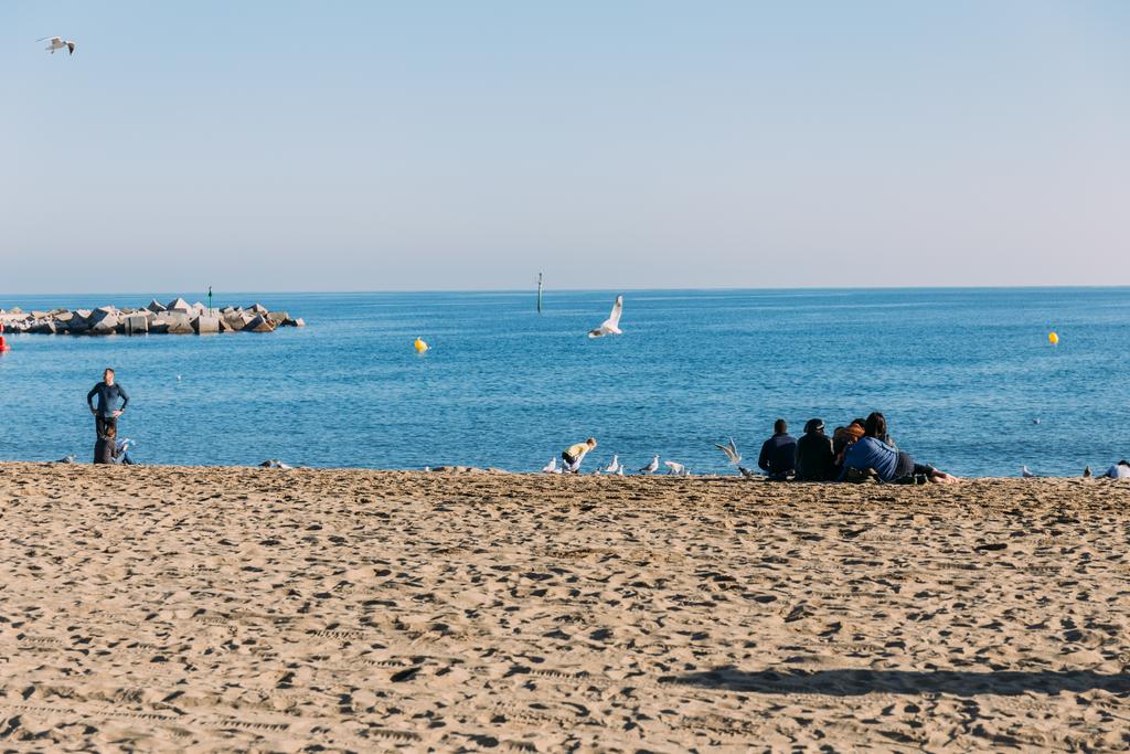 バルセロナ, スペイン - 2018 年 12 月 28 日: 海、ビーチに座っている人々 の風光明媚なビュー  - 写真・画像