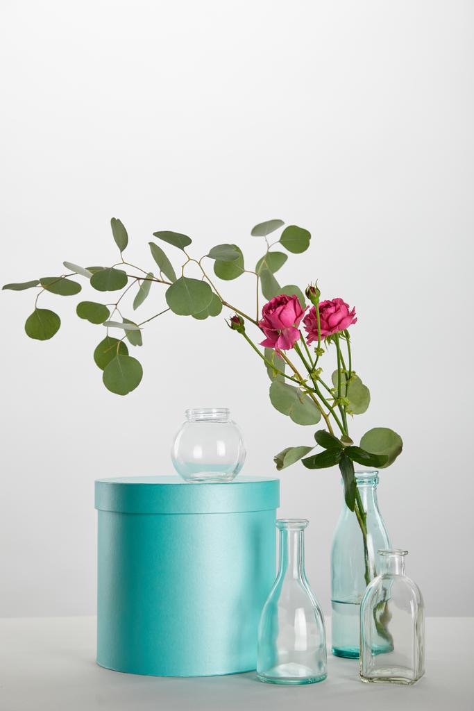 新鮮なピンクのバラと白で隔離の青緑色のギフト ボックスを透明なボトルにユーカリ - 写真・画像