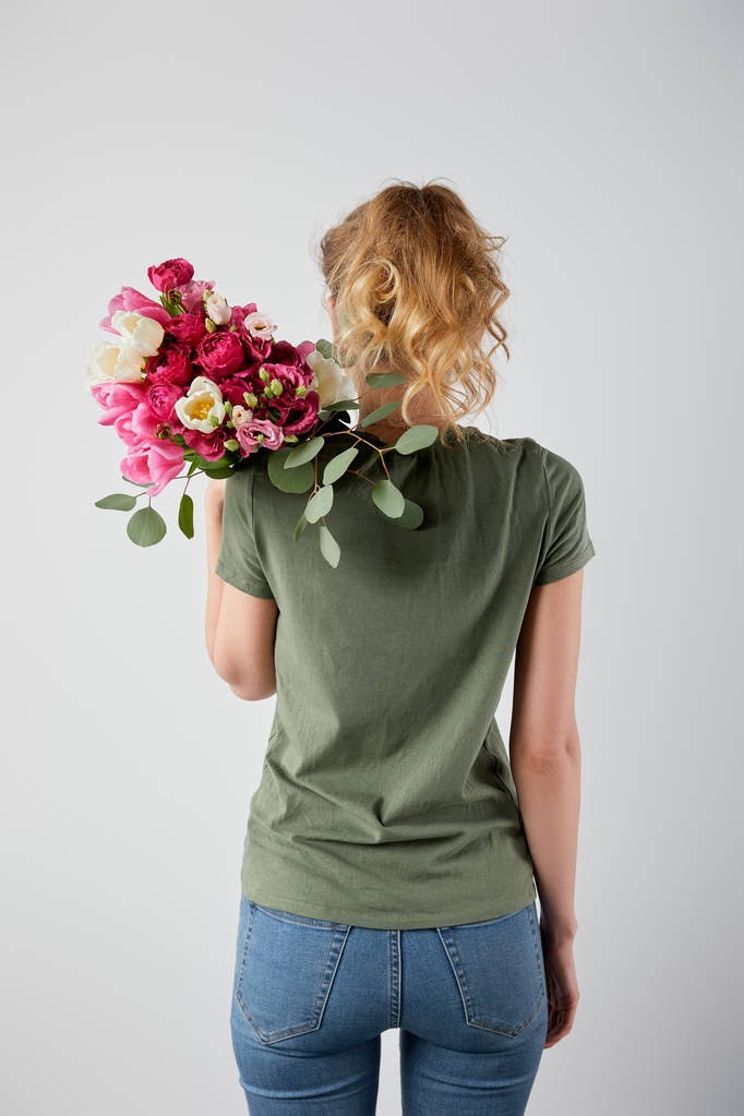 вид сзади девушки, держащей букет с тюльпанами и розами, изолированными на сером
 - Фото, изображение
