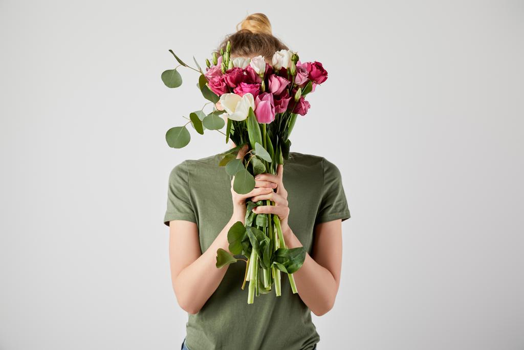 дівчина тримає букет з тюльпанами, евкаліптом і трояндами перед обличчям ізольовано на сірому з місцем для тексту
 - Фото, зображення