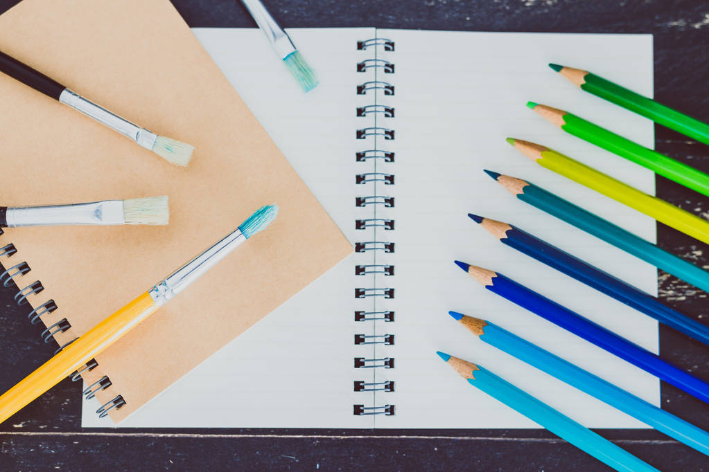 íróasztal jegyzettömbök és akvarell ecset és színes ceruzák, wi - Fotó, kép