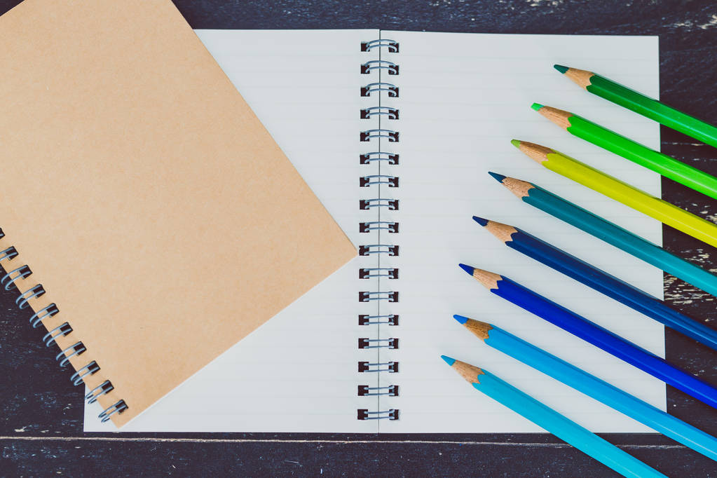письменный стол с блокнотами и цветные карандаши с пустыми страницами и ко
 - Фото, изображение