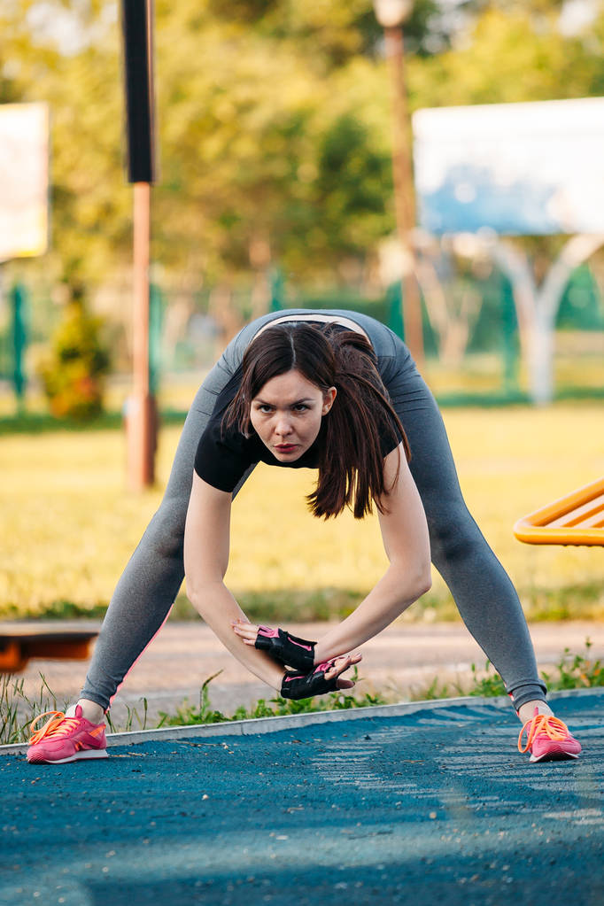 young athletic woman doing exercises leaning forward in Park out - Photo, Image