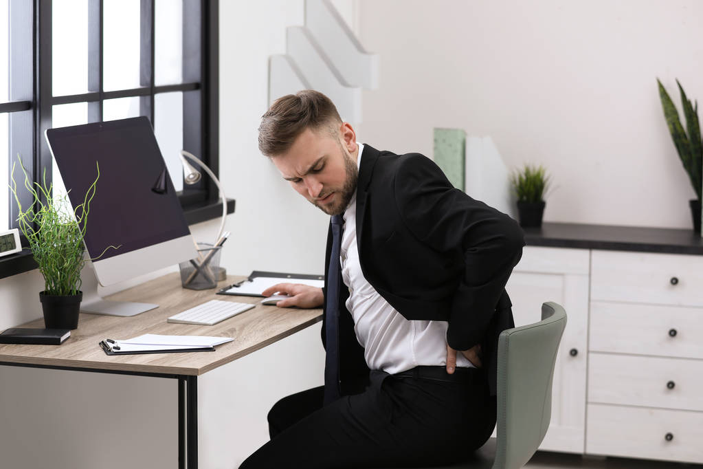 Бизнесмен, страдающий от болей в спине на рабочем месте
 - Фото, изображение