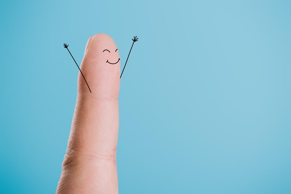 обрезанный вид одного пальца со счастливым лицом, изолированным на голубом
 - Фото, изображение