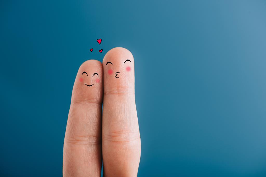 vista cortada de casal sorridente de dedos com corações isolados em azul
 - Foto, Imagem