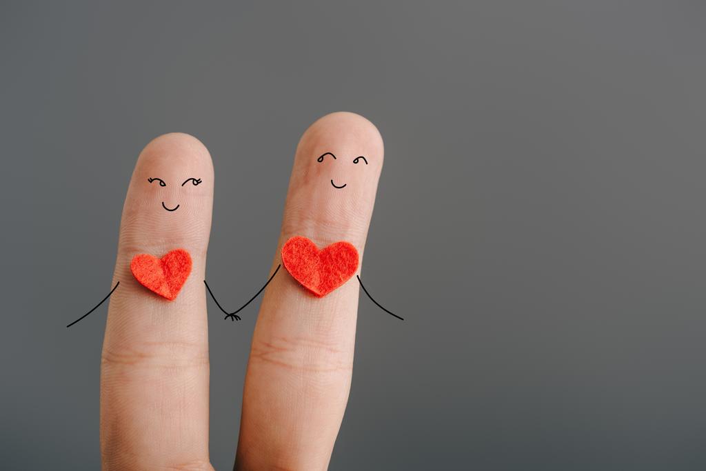 vista cortada de casal feliz de dedos com corações segurando as mãos isoladas em cinza, conceito dia dos namorados
 - Foto, Imagem