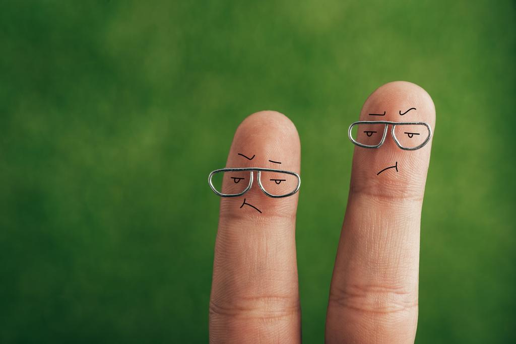 обрізаний вид розчарованих пальців в поганому настрої на зеленому
 - Фото, зображення