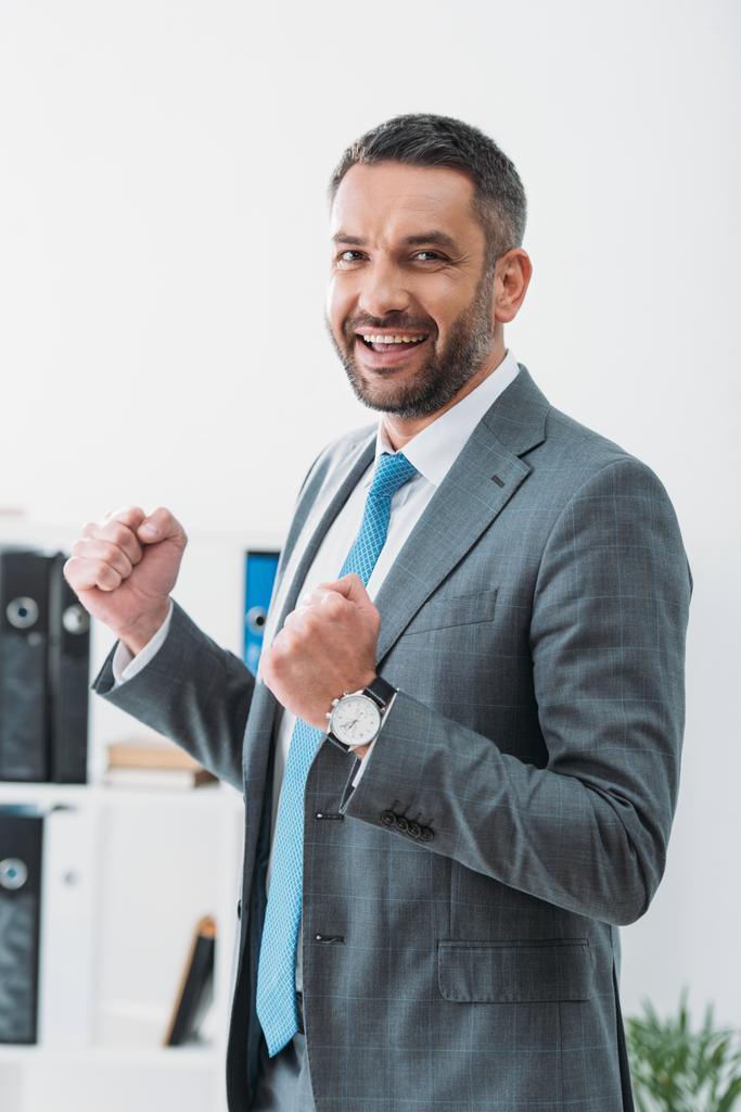 guapo hombre de negocios en traje gris mostrando sí gesto en la oficina
 - Foto, imagen