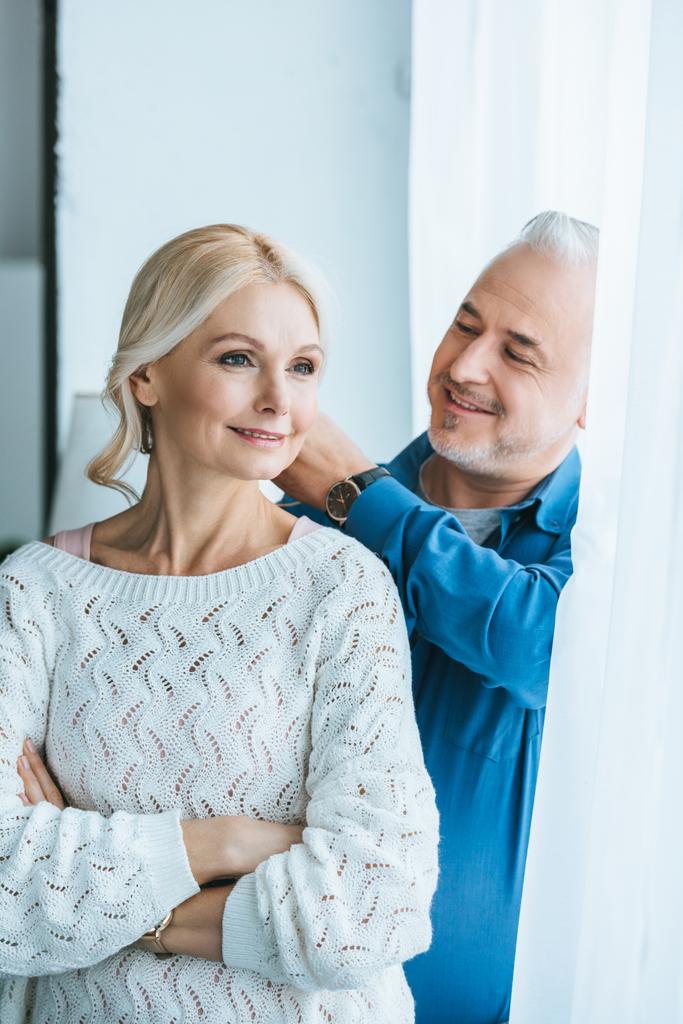 happy man touching blonde hair of smiling wife at home - Photo, Image