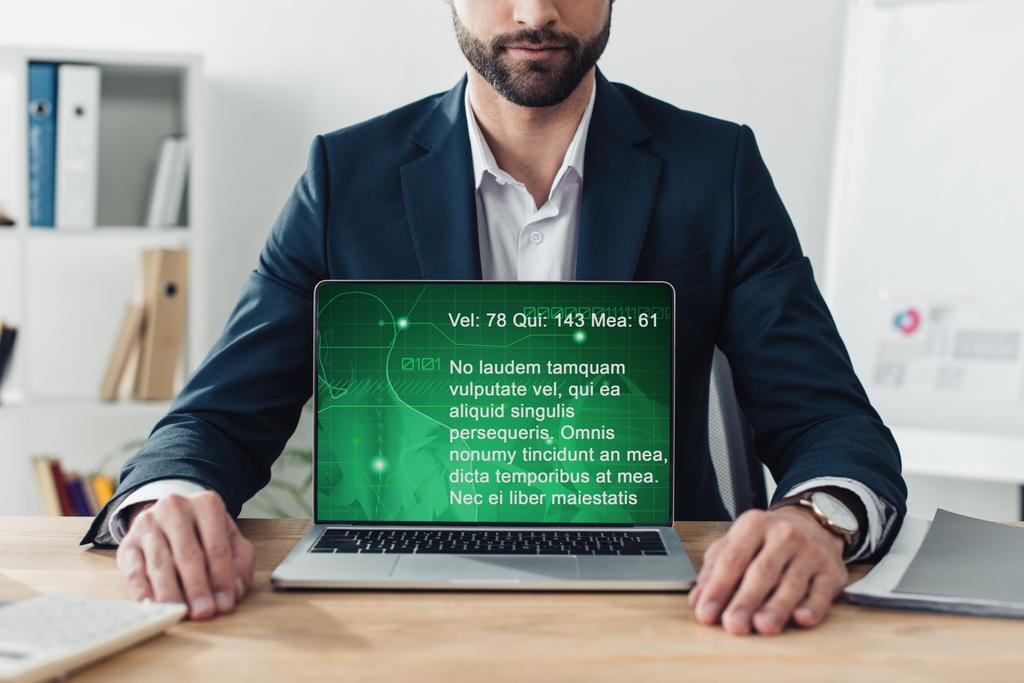 частковий вигляд радника в костюмі, який показує ноутбук з веб-сайтом на екрані в офісі
  - Фото, зображення