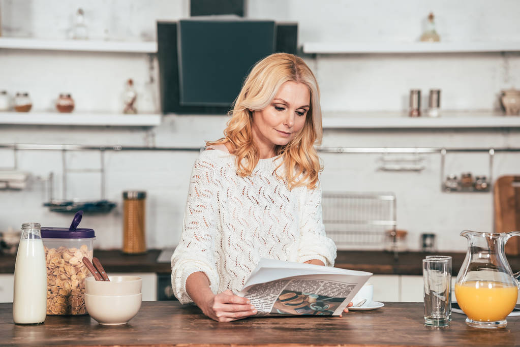 atrakcyjny blond kobieta czytanie gazety w kuchni  - Zdjęcie, obraz