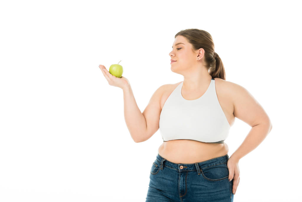 Gelukkig lachende overgewicht vrouw kijken naar groene appel geïsoleerd op wit - Foto, afbeelding