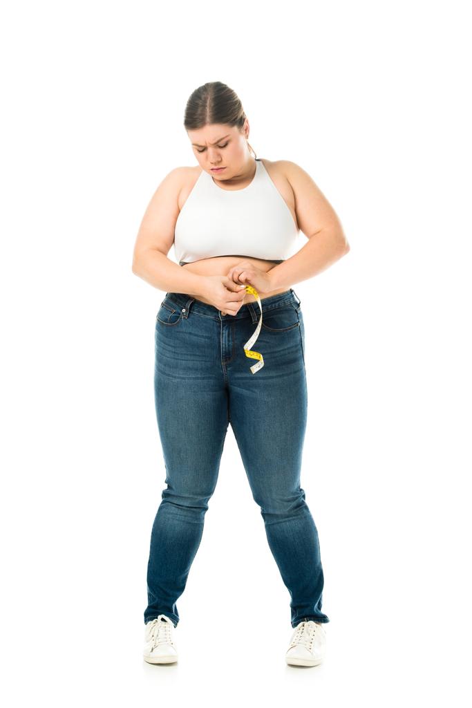 zdenerwowany nadwaga kobiety w dżinsach pomiar talii z miara na białym tle, stracić wagi bagażu - Zdjęcie, obraz