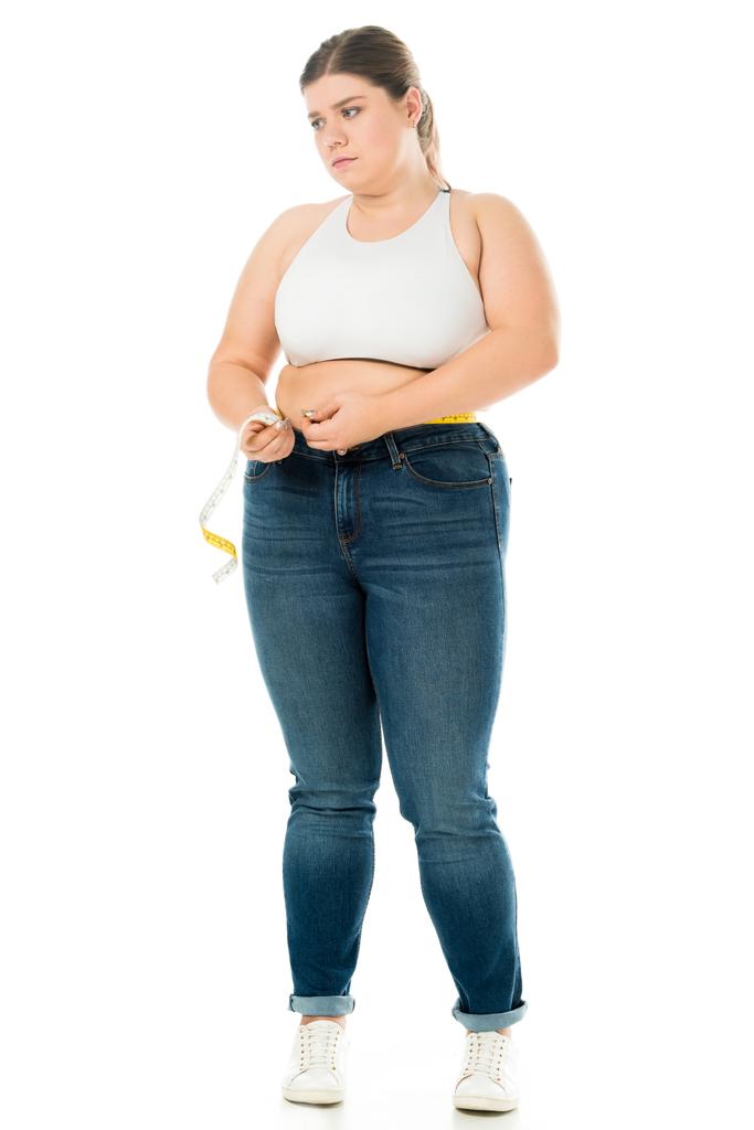 незадоволена надмірна вага жінки в джинсах вимірювальна талія з вимірювальною стрічкою ізольована на білому фоні, концепція схуднення
 - Фото, зображення