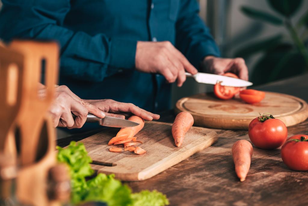 selective focus of couple cutting carrot and tomato in kitchen - Photo, Image