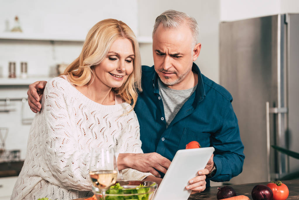 enfoque selectivo de pareja mirando tableta digital en la cocina
 - Foto, Imagen