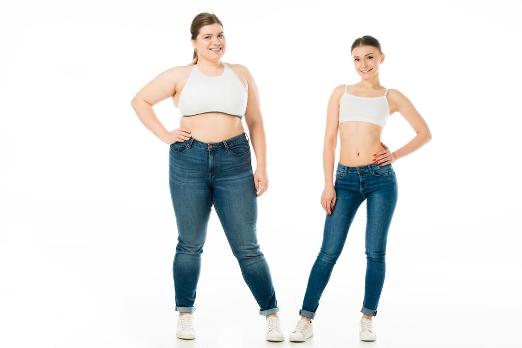 happy slim and overweight women in denim posing together isolated on white, body positivity concept  - Photo, Image
