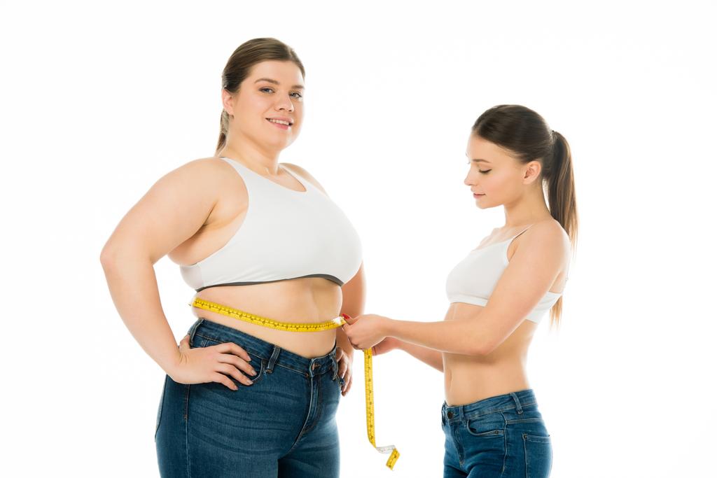 slim woman measuring waist of happy overweight woman isolated on white, body positivity concept - Photo, Image