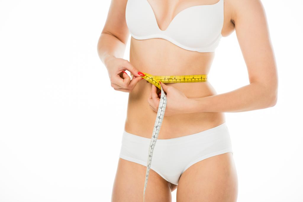 cropped view of slim woman in underwear measuring waist with centimeter isolated on white - Photo, Image