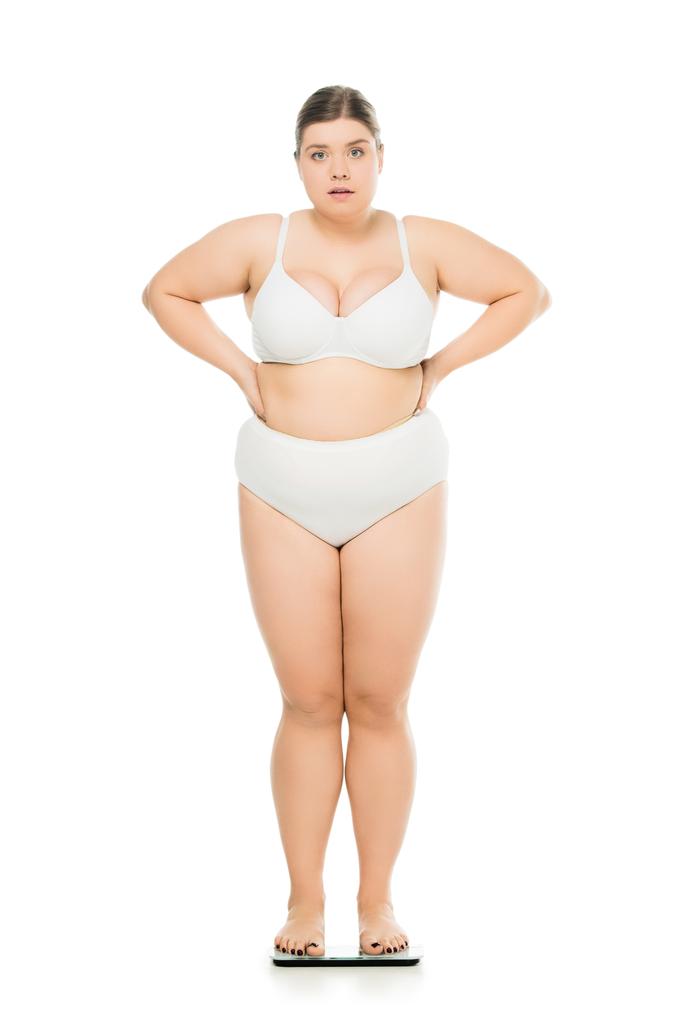 molesto joven mujer con sobrepeso de pie en escamas aisladas en blanco, perder peso concepto
 - Foto, Imagen