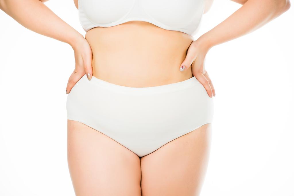 abgeschnittene Ansicht einer übergewichtigen Frau, die mit den Händen auf der Taille posiert, isoliert auf weißem, Körper-Positivitäts-Konzept - Foto, Bild