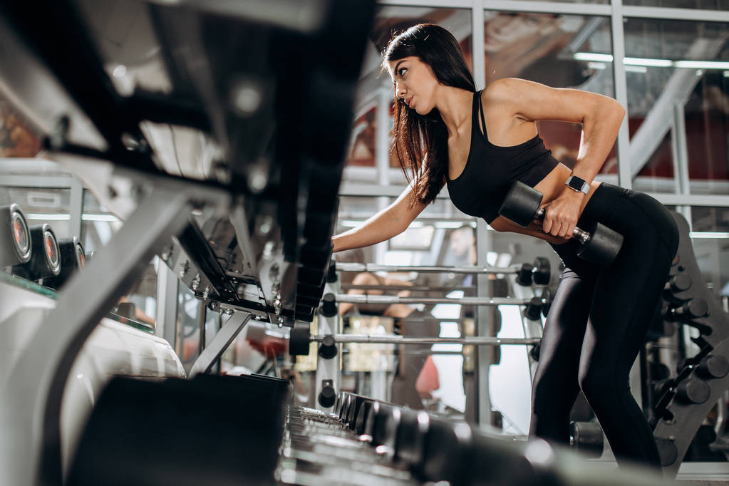 Karcsú lány, fekete sport ruhák öltözött csinál tricepsz edzés az edzőteremben súlyzó - Fotó, kép