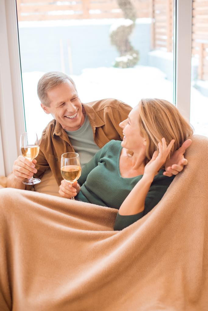 柔らかいフリース毛布の下で休憩しながら白ワインのグラスを持って幸せなカップル - 写真・画像