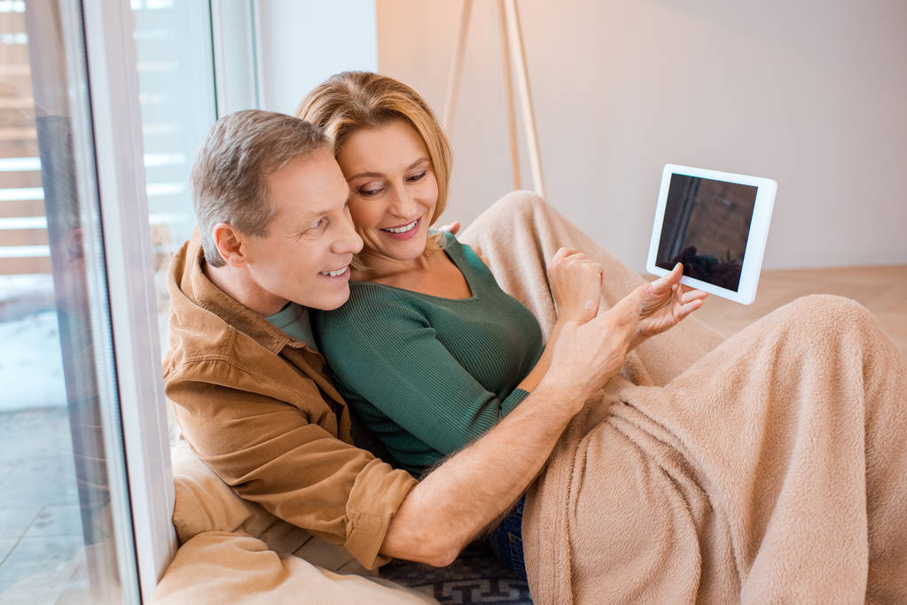 couple heureux en utilisant une tablette numérique tout en étant assis sous la couverture polaire
 - Photo, image