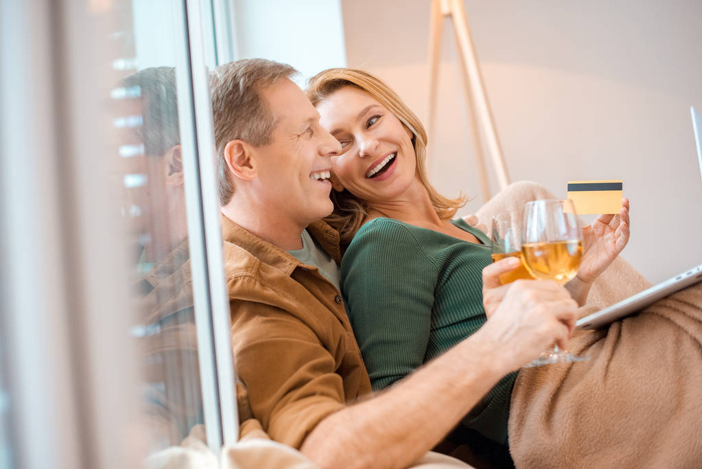 ridere coppia che tiene i bicchieri di vino bianco mentre seduto alla finestra a casa
 - Foto, immagini