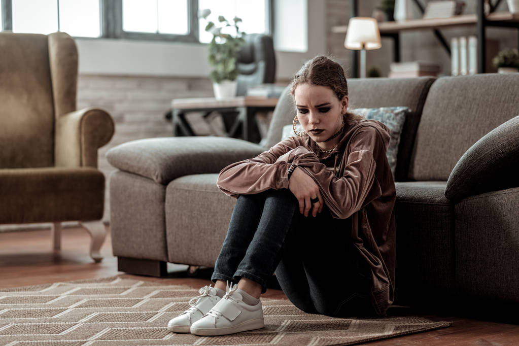 Adolescente chica usando zapatillas blancas sentado en el suelo sensación de estrés
 - Foto, imagen
