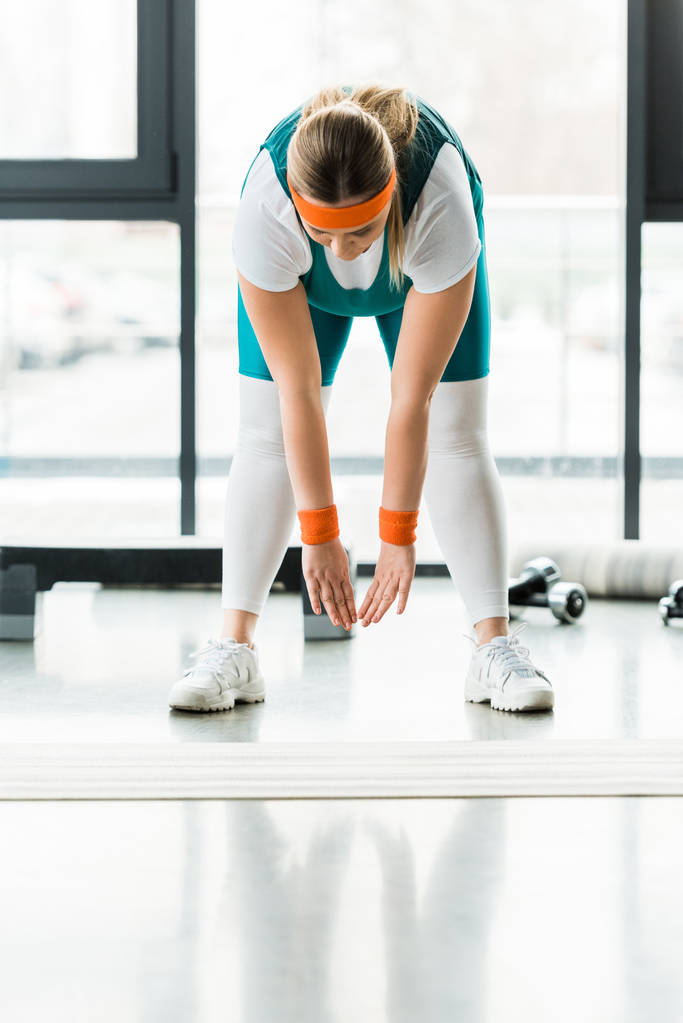 túlsúlyos nő nyújtás a Sportruházat közeli fitnesz szőnyeg - Fotó, kép