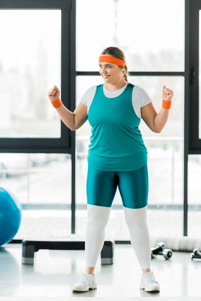 smiling overweight woman training in sportswear in gym - Photo, Image