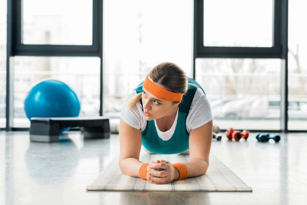menina com sobrepeso fazendo exercício prancha no tapete de fitness
  - Foto, Imagem