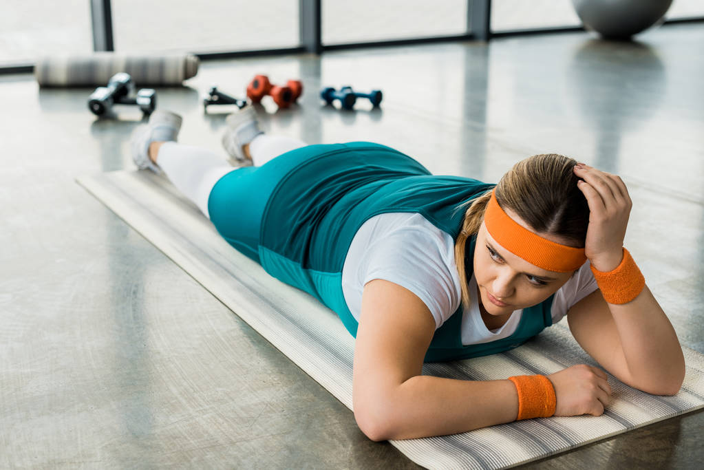 kimerült túlsúlyos lány feküdt edzőteremben fitness szőnyeg - Fotó, kép