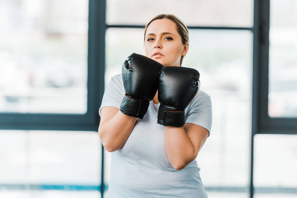 ciddi kilolu kız spor salonunda boks eldiven ayakta - Fotoğraf, Görsel