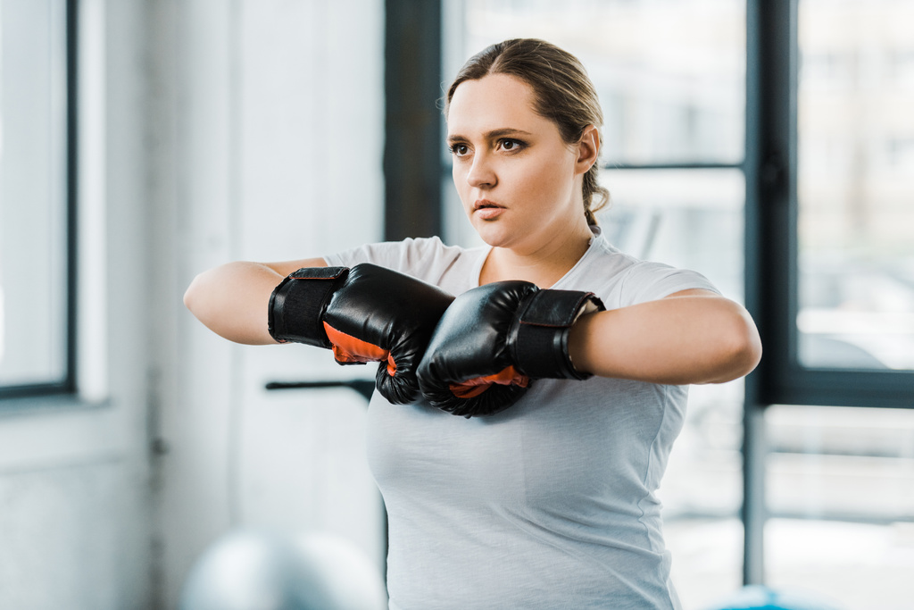 уверенная девушка с избыточным весом, стоящая в боксерских перчатках
 - Фото, изображение