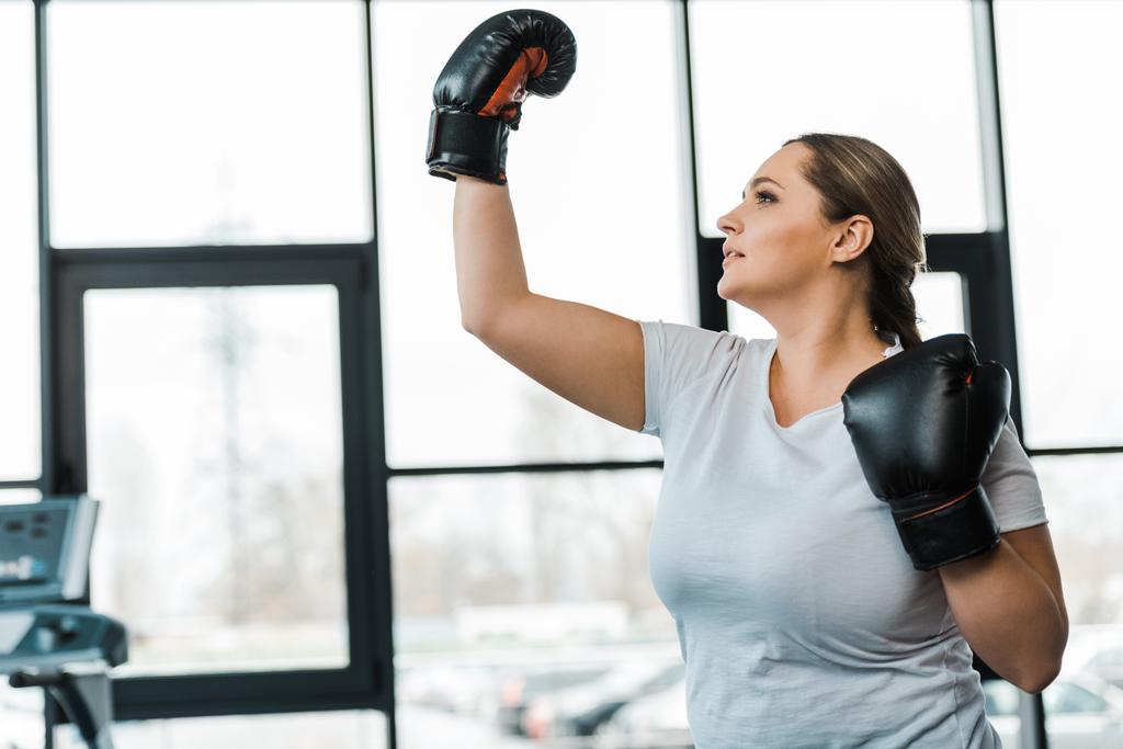  overweight woman wearing boxing gloves practicing kickboxing in gym - Photo, Image