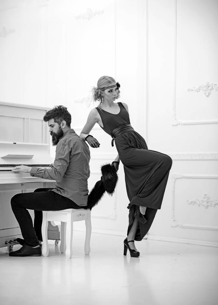 Yirmili güzel kız elbise ve ona beyaz arka plan üzerinde izole eğilerek yaka kürk piyano şık saçlı sakallı adam - Fotoğraf, Görsel