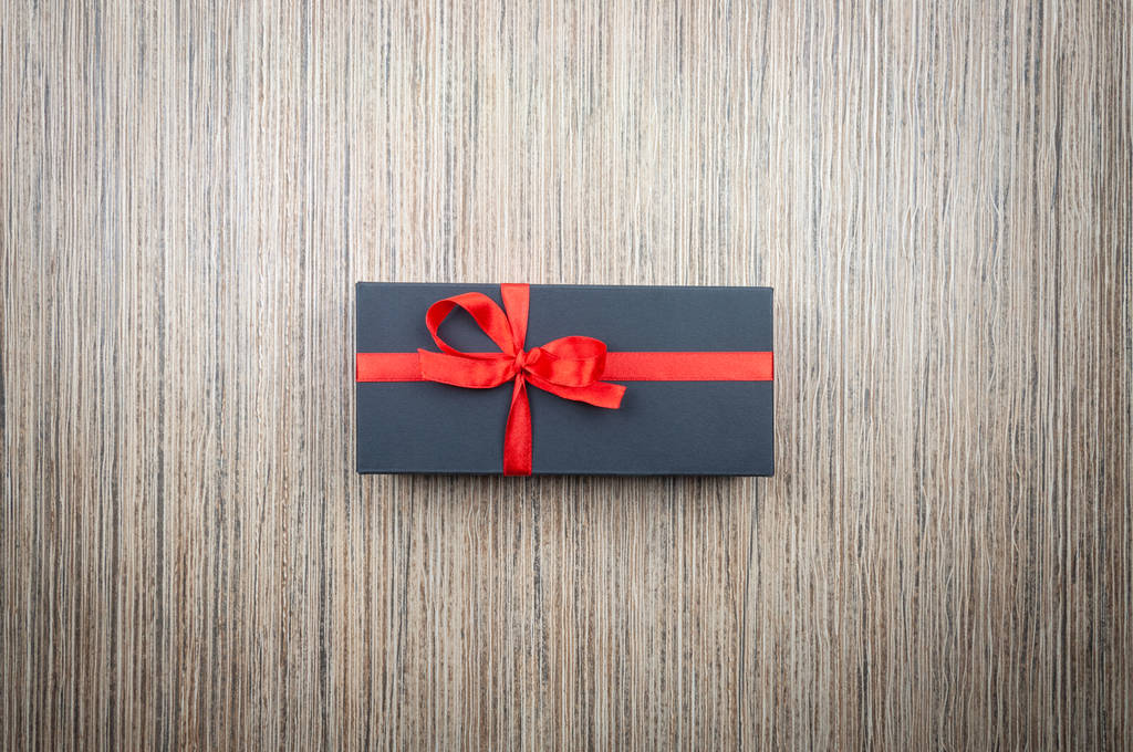 Черные подарочные коробки с бантиком на деревянном столе
 - Фото, изображение